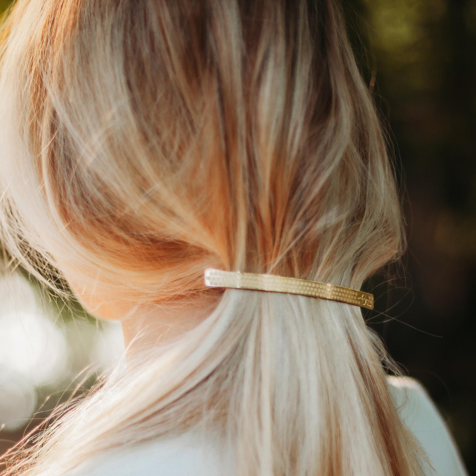 FEMME DONT LES CHEVEUX SONT RETENUS PAR UNE BARRETTE FINE ET LONGUE DOREE ET DECOREE D'UN MOTIF PETITES FLEURS