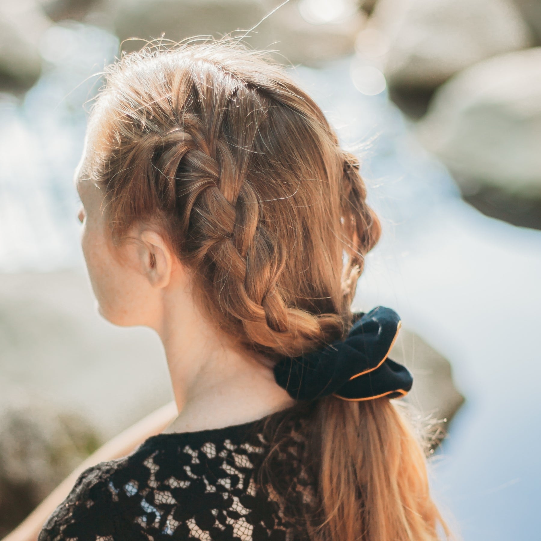 FEMME VUE DE DOS PORTANT UNE QUEUE DE CHEVAL RETENUE PAR UN CHOUCHOU NOIR EN VELOURS DE COTON BIO ET LISERE EN SOIE DORE