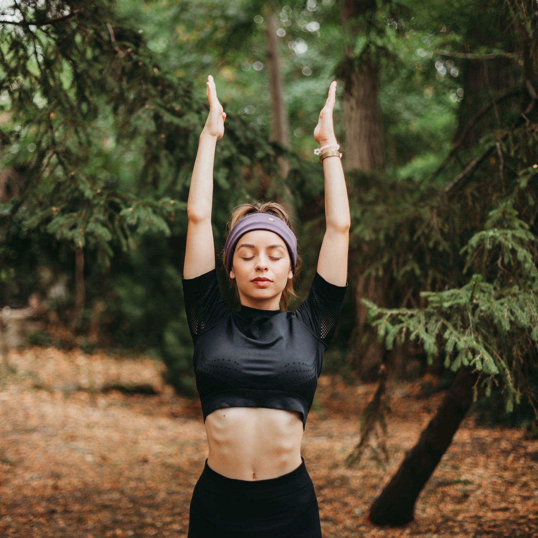 FEMME LES BRAS LEVES PORTANT UN BANDEAU VIOLET DE SPORT