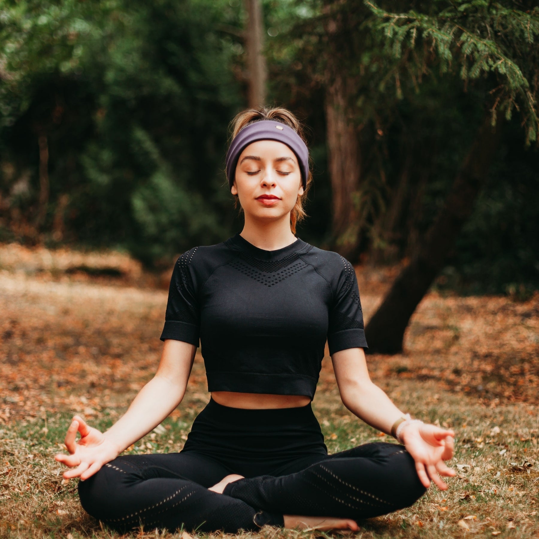 FEMME EN POSITION DE LOTUS PORTANT UN BANDEAU VIOLET DE SPORT