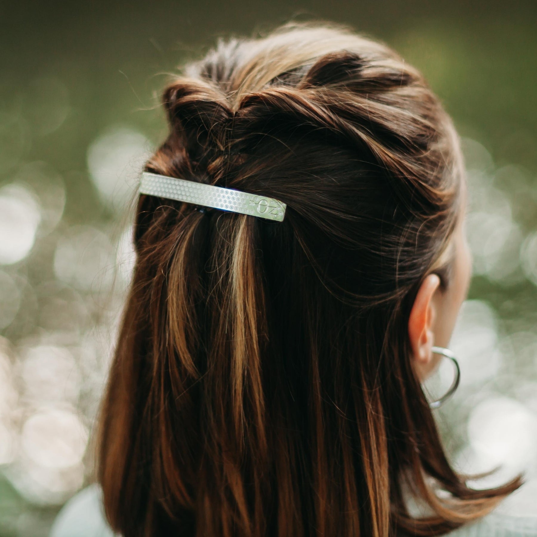 FEMME VUE DE DOS PORTANT UNE BARRETTE ARGENTEE DECOREE DE MOTIFS FLEURS