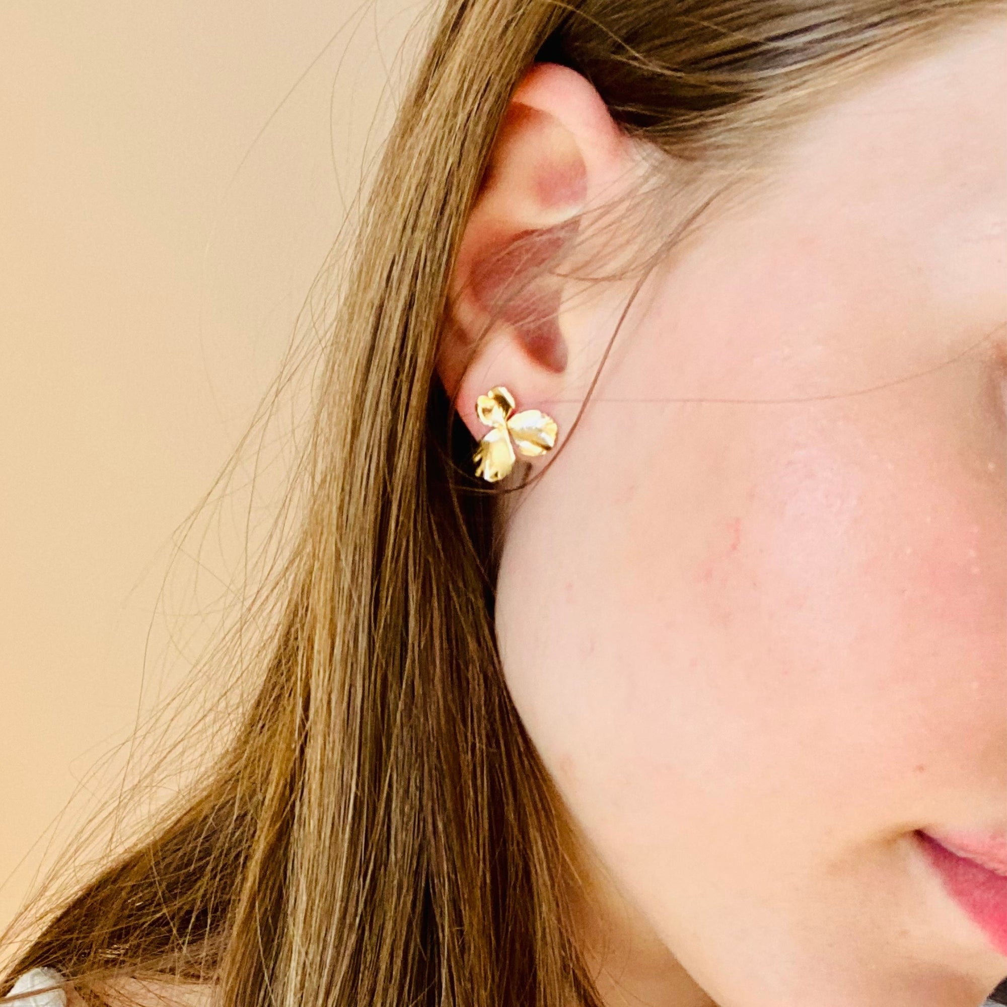Femme portant des boucles d'oreilles anti allergie fabriquées en France puces dorées fleur