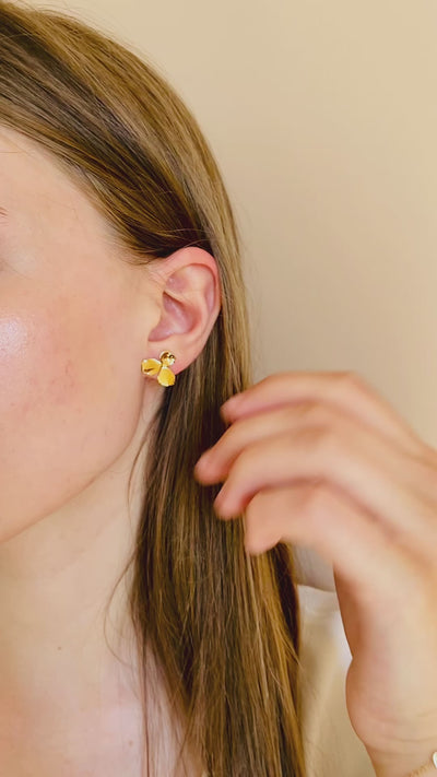 Femme avec des boucles d'oreilles fabriquées en France puces dorées fleur anti allergies