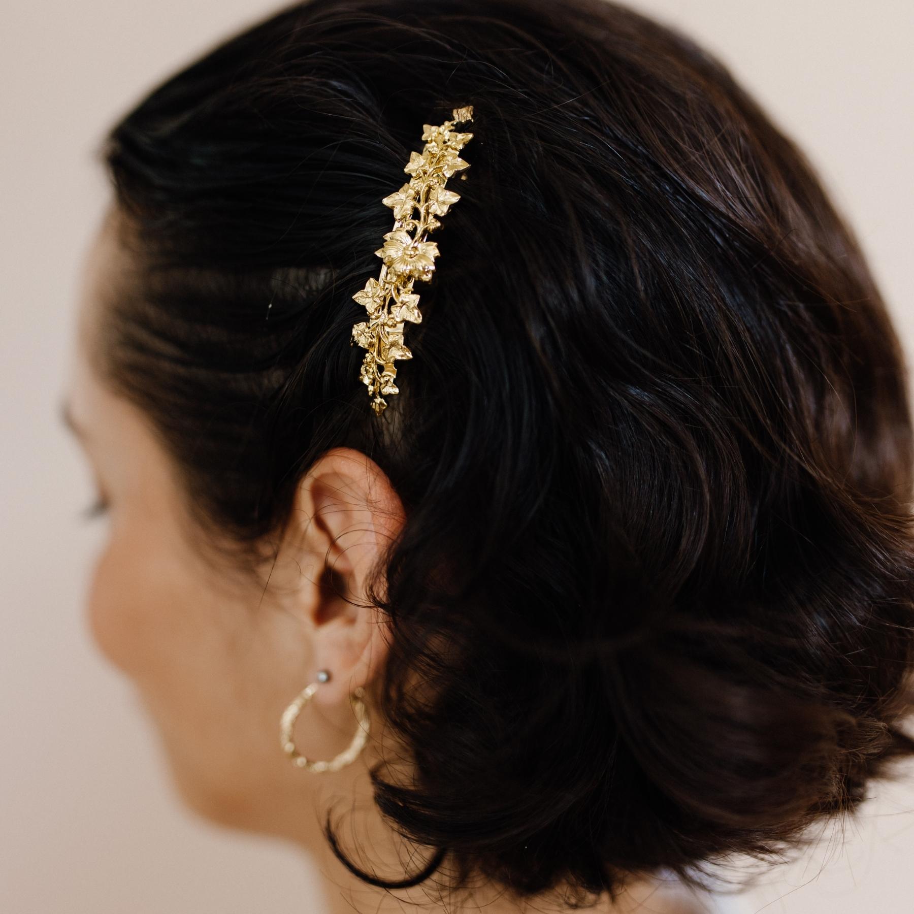 Coiffure femme cheveux courts décorée d'une petite barrette dorée fleurie 